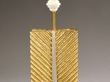 a gold and white table lamp with a white shade on top of it