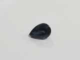 a blue sapphire tear shaped stone on a white surface