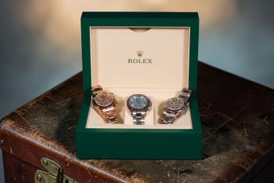 trois montres posées dans une boîte, sur une valise