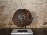 une sculpture représentant un disque en bois posé sur un socle