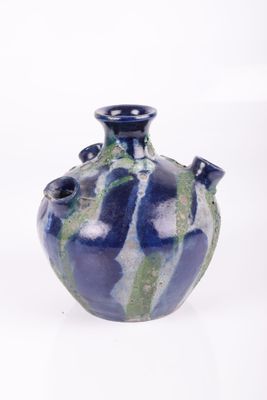 un vase bleu et vert posé sur une surface blanche