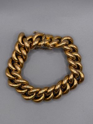 gros plan d'un bracelet en or sur une surface grise