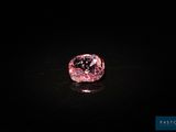 un diamant rose sur une surface noire dans l'obscurité