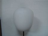 a white vase on a black stand against a white wall