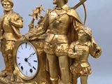 a gold clock with a statue of a man holding a sword