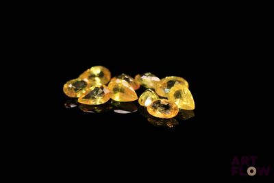 yellow sapphires on a black surface with reflection