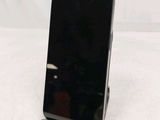 a black cell phone sitting on a stand on a table