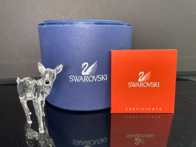 une figurine de cerf en verre à côté d'une boîte de Swarovski