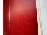 l'image d'un livre rouge posé sur une surface blanche