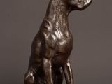 a bronze statue of a dog sitting on top of a wooden table