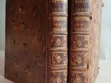 two old books are sitting side by side on a white surface