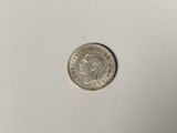 a silver coin on a white surface with a white background