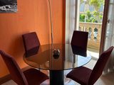a glass table and chairs in a room with orange walls