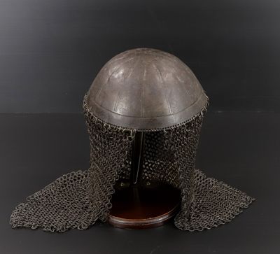 un vieux casque recouvert de cotte de mailles sur un fond noir