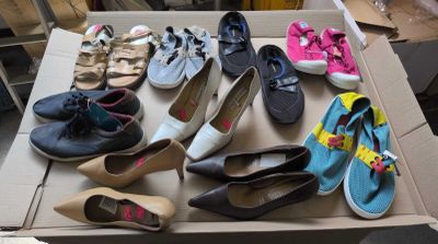 plusieurs paires de chaussures dans une boîte posée sur le sol