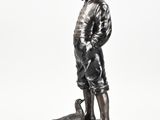 bronze statue of a boy with a bird on a rock
