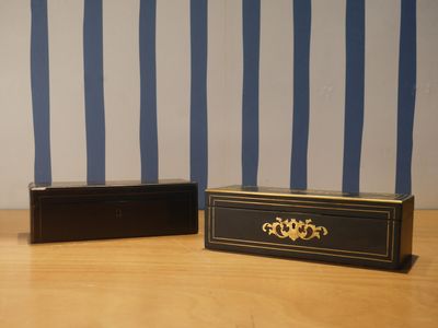 deux boîtes noires posées sur une table en bois recouverte d'un papier peint à rayures bleues et blanches