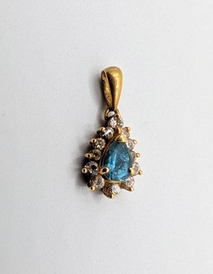 a close up of a blue stone and diamond pendant on a white surface