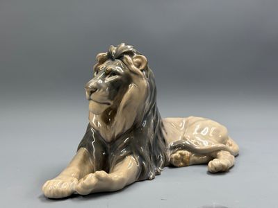 statue of a lion laying down on a gray surface