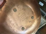 a person holding a large copper pan in their hand
