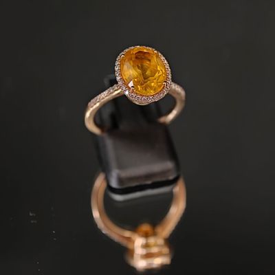 une bague sertie d'un saphir jaune et de diamants, posée sur un fond noir