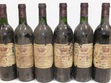 six bottles of wine are lined up in a row on a white surface