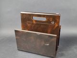 a metal magazine holder with a handle on a gray background