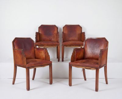 quatre fauteuils en cuir marron placés les uns à côté des autres sur une surface blanche