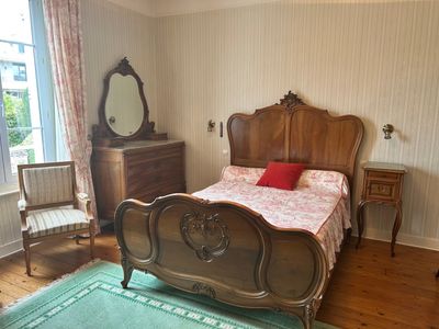 a bedroom with a bed, dresser, mirror, and chair