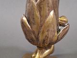 a gold vase with a flower on it on a table