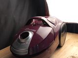 un aspirateur rouge et argent posé sur une table en bois