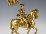 a gold statue of a man on a horse holding a flag