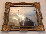 a mirror hanging on the wall with a chandelier in the background