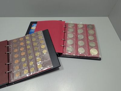 deux classeurs remplis de pièces de monnaie, posés sur une table