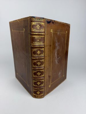 un vieux livre marron avec des bordures dorées et une couverture aux bordures dorées