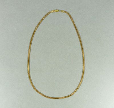 un collier en or avec une chaîne sur fond blanc