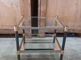 a glass and brass coffee table in the middle of a room