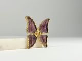 a close up of a purple butterfly broochle on a white surface