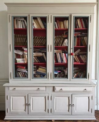 une bibliothèque blanche sur laquelle sont posés de nombreux livres