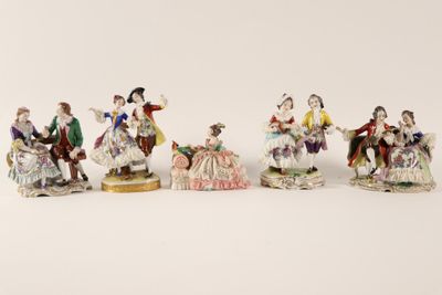 a group of six figurines of people sitting on a white surface