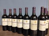 six bottles of wine are lined up on a wooden table