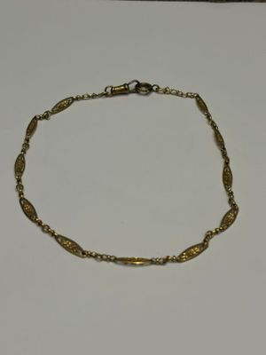 gros plan d'un bracelet en or sur une surface blanche