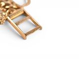a gold necklace with a ladder on it on a white surface