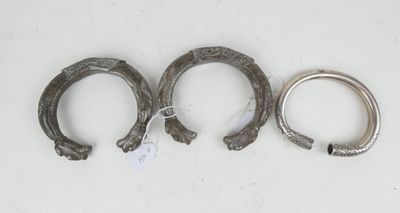 trois fers à cheval en argent, munis d'étiquettes, posés sur une surface blanche
