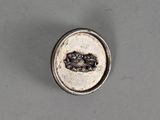 an oval silver broochle with a picture of a man and a woman on it