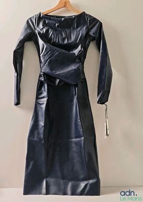 black leather dress hanging on a hanger against a white wall