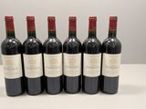 six bouteilles de vin rouge sont alignées sur une table