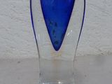 un vase en verre bleu posé sur une table blanche