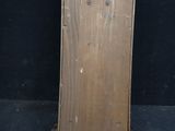 a small wooden clock on a stand against a black background