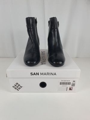 une paire de bottines en cuir noir posée sur une boîte blanche